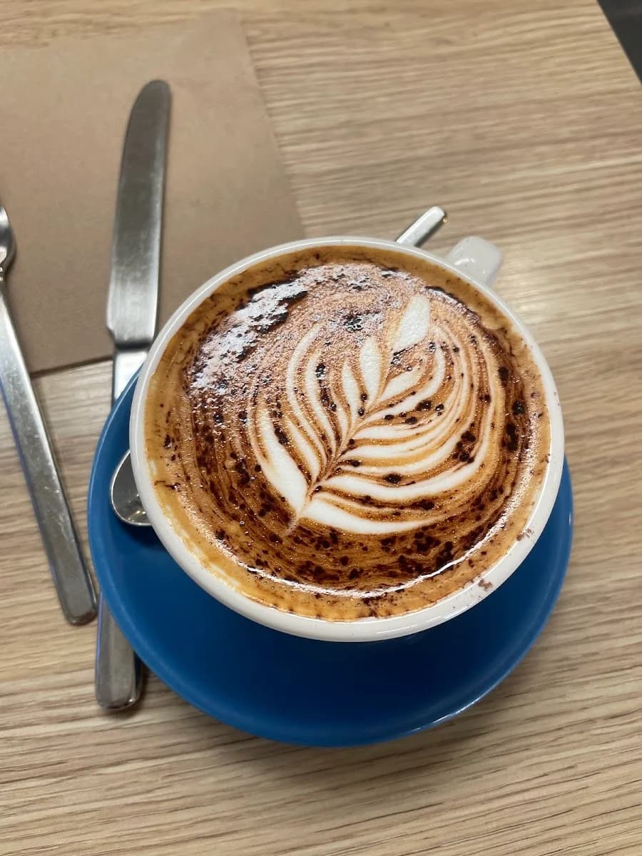 Coffee with intricate latte art in a blue cup at the cafe